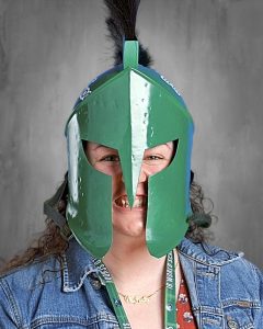 Una persona que lleva un casco espartano verde y una chaqueta vaquera, con una amplia sonrisa.